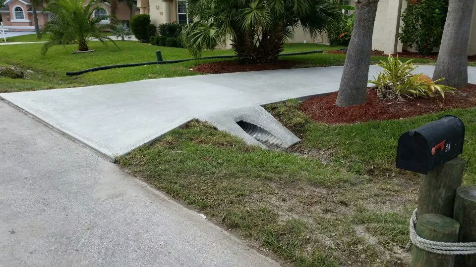 New concrete driveway extension and drainage work on a residential job site