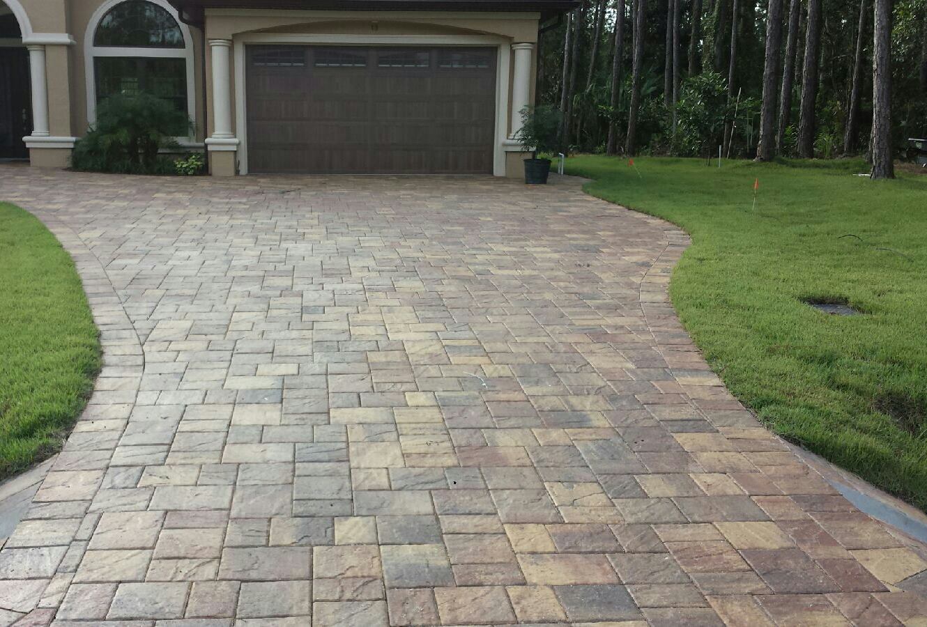 Finished paver driveway in front of a house with a wood garage door