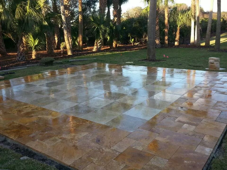 Large finished travertine paver patio surrounded by palm trees